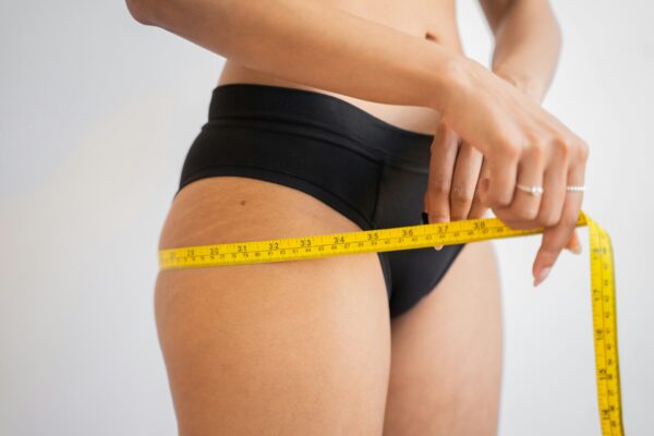 1778068990 picture of woman measuring thigh circumference to show fat deposits on posterior and anterior thigh 600x400